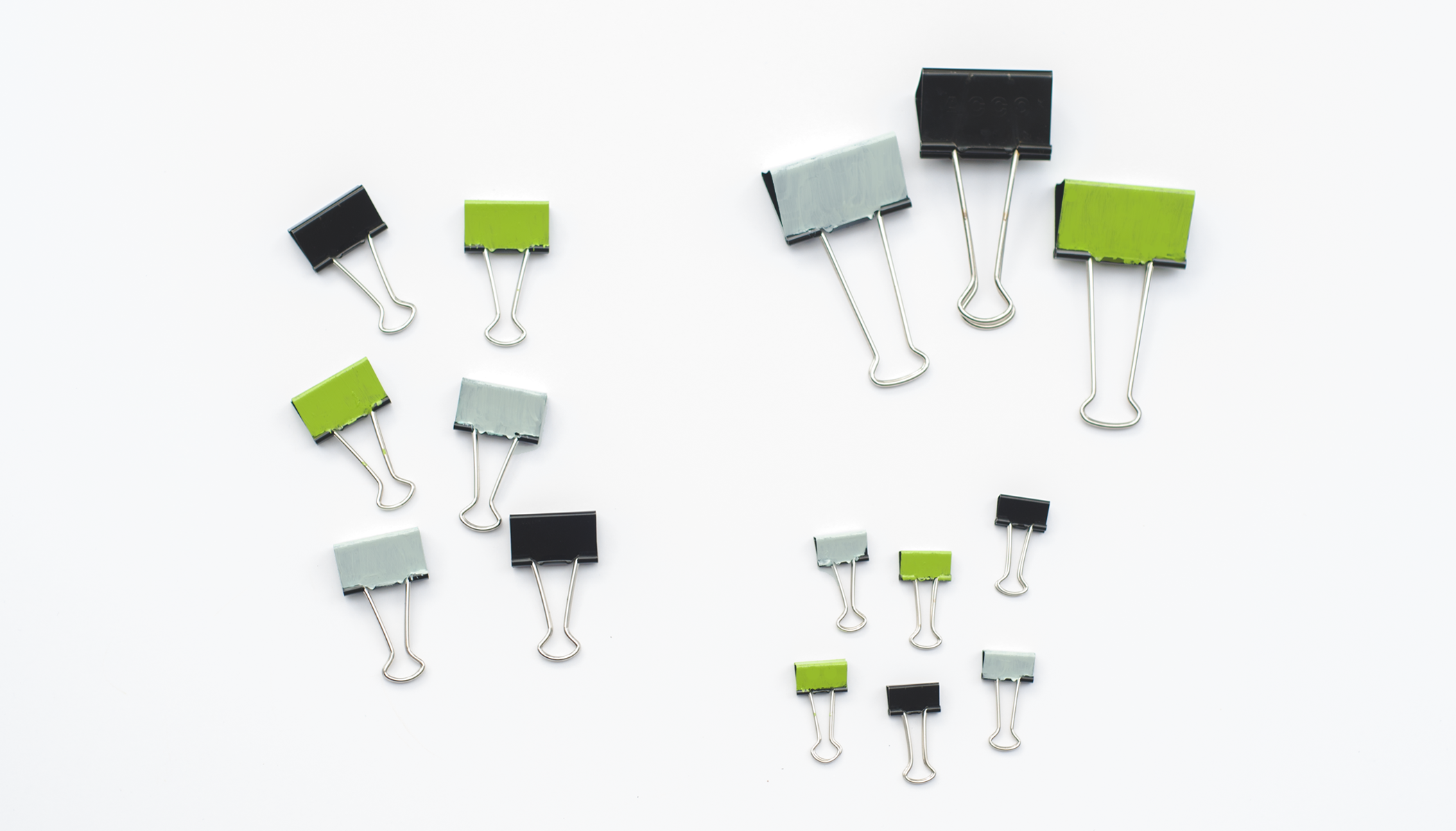 A collection of 15 binder clips. There are small, medium, and large clips 
and black, grey, and green clips.